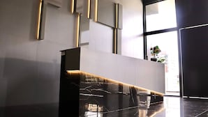 A modern reception desk with a sleek design, a marble countertop, and a glass partition. - Apart no Mardisa Design por Carpediem (João Pessoa)