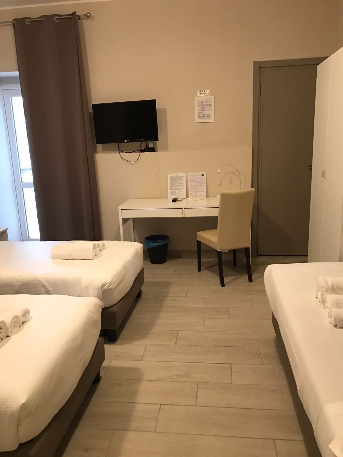 Een hotelkamer met twee bedden, een bureau, een stoel, een televisie en een deur.