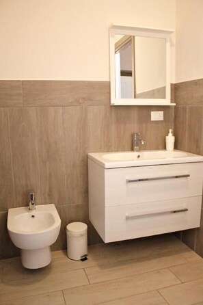 Un baño con lavamanos, espejo y bidé blancos.