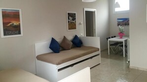 Una sala de estar moderna con un sofá blanco, una mesa de comedor y una pequeña cocina.