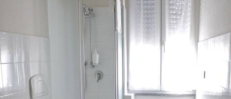 A small, white bathroom with a toilet, bidet, and shower stall.
