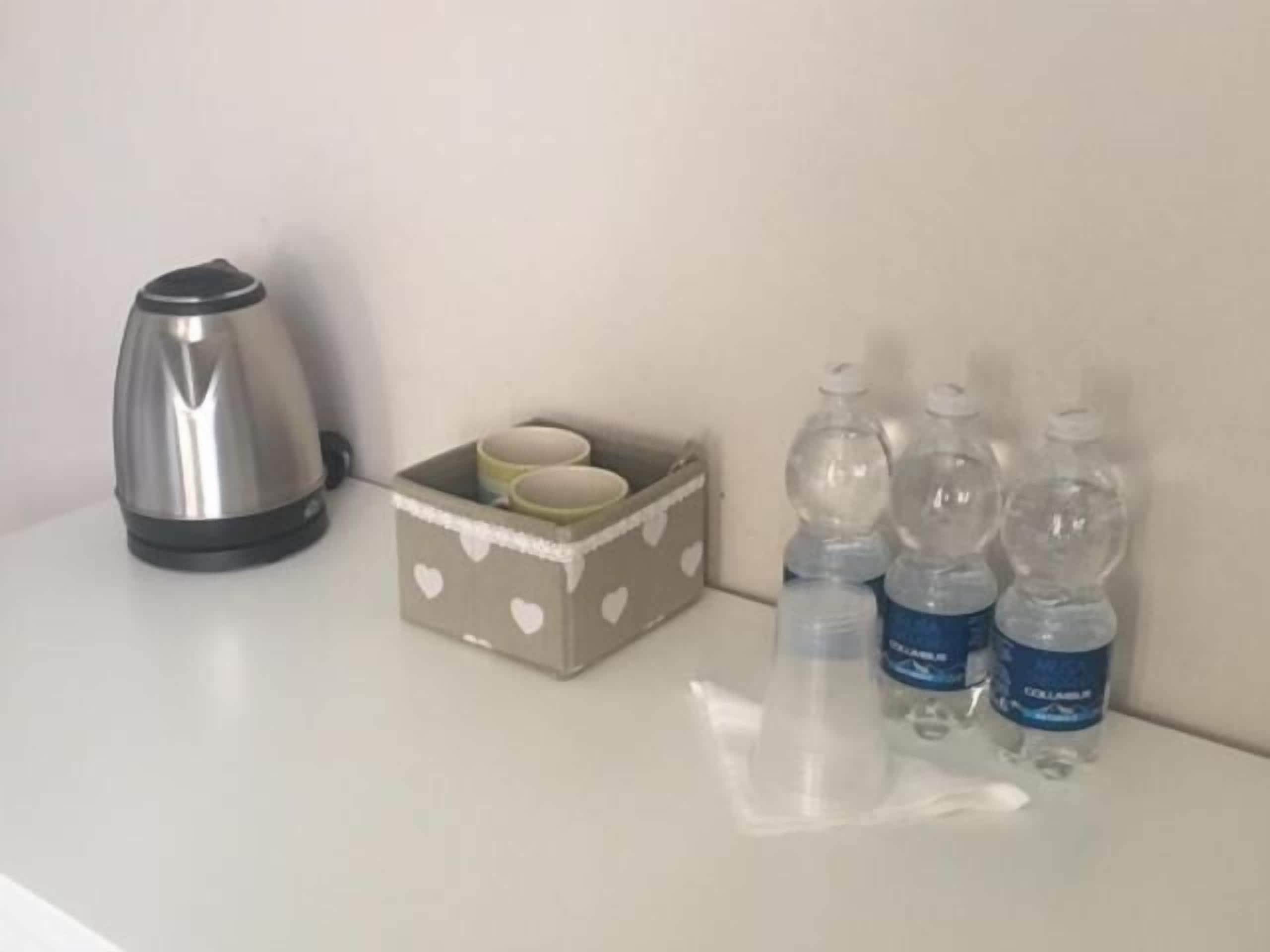 Eine Küchenarbeitsplatte mit einem Wasserkocher, einer schachtelartigen Aufbewahrung mit Herzmuster und mehreren Wasserflaschen.