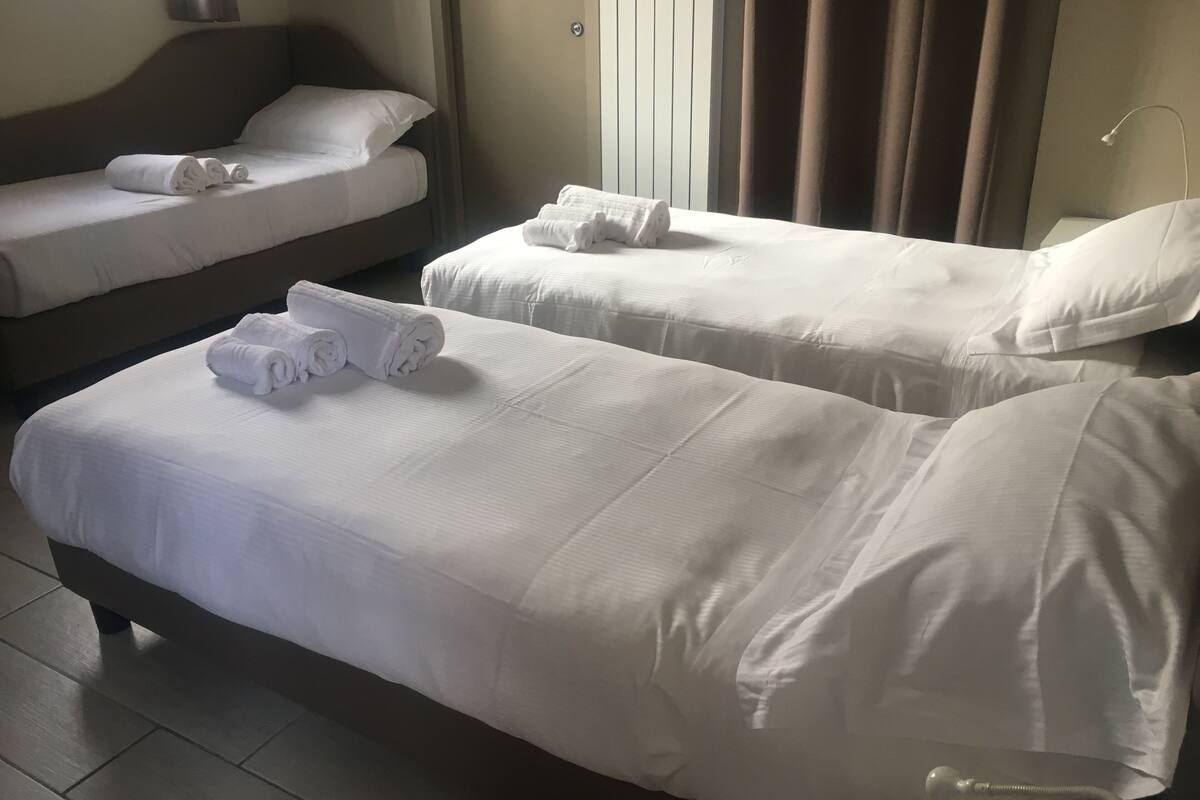 A hotel room with two single beds, each with neatly folded white towels.