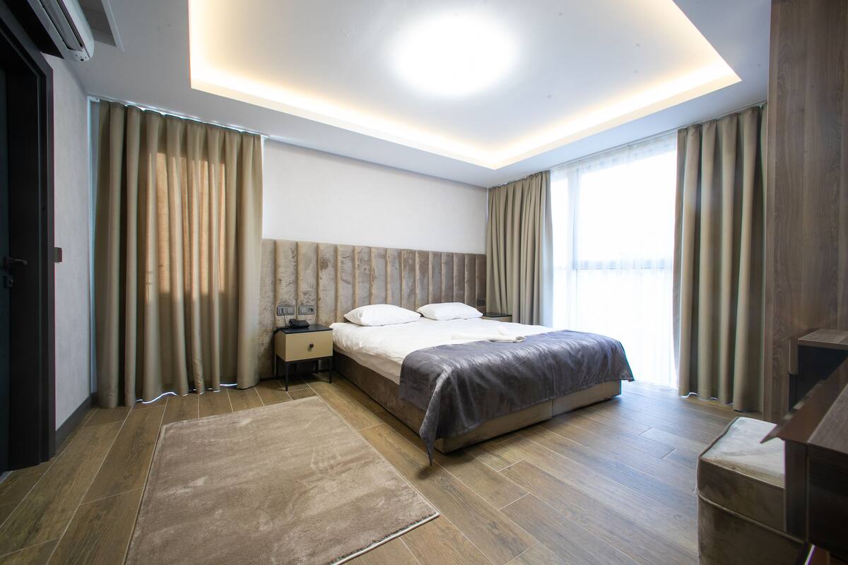 Un dormitorio moderno con una cama grande, suelo de madera y una lámpara en el techo.