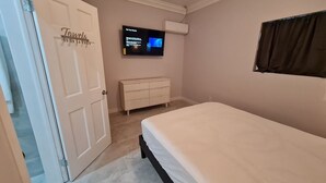 A bedroom with a bed, a dresser, a TV mounted on the wall, and a door labeled "Towels".