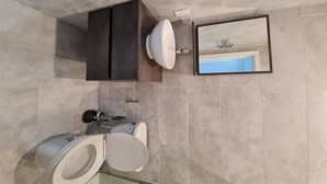 A bathroom with a toilet, sink, and mirror.