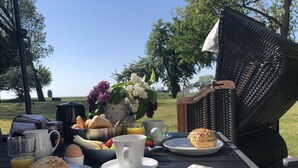 Un montaje para picnic con comida, bebidas y un periódico sobre una mesa al aire libre.