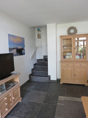 A living room with a TV, wooden cabinet, and a staircase.