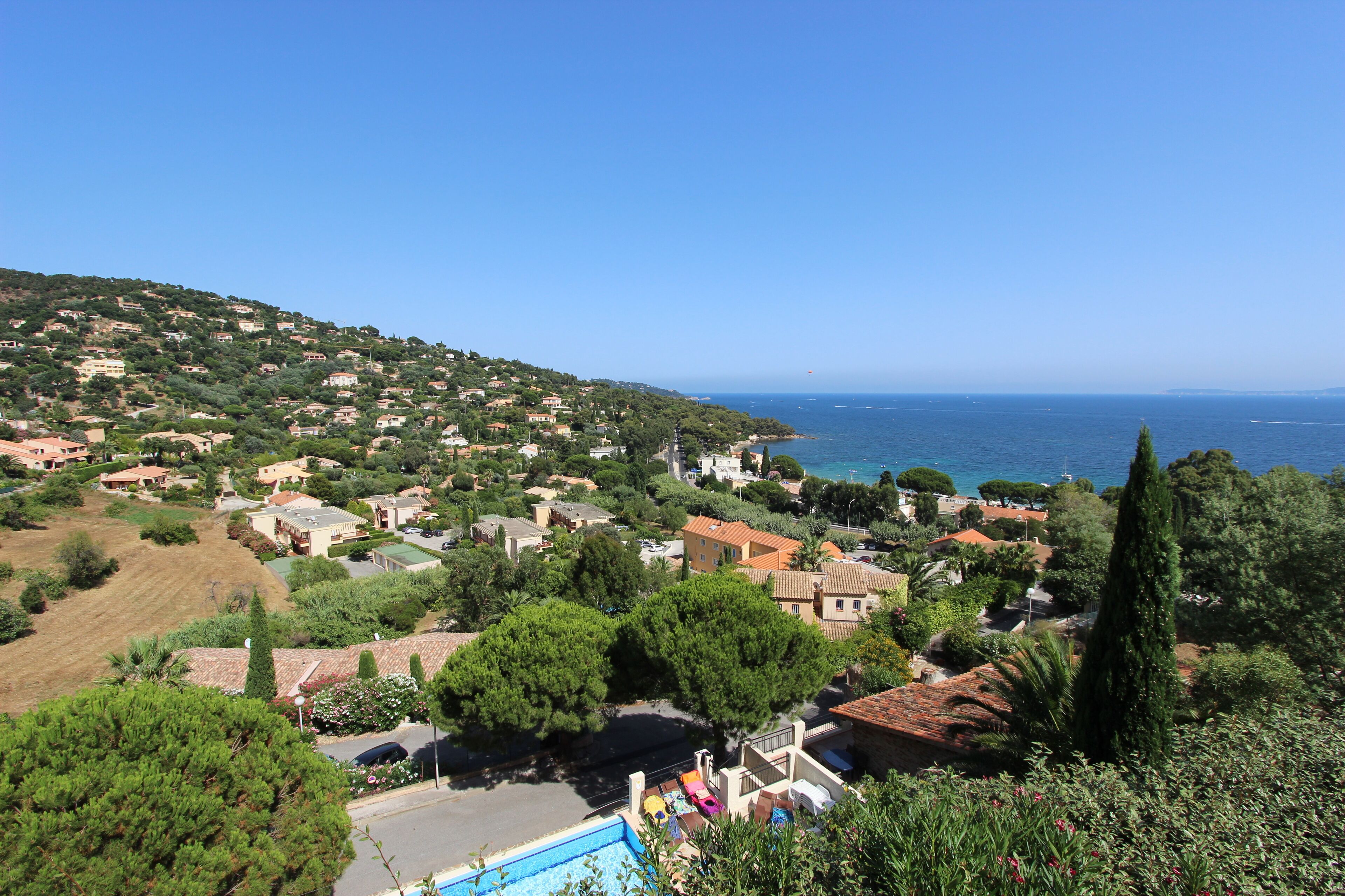 A coastal residential area with houses, a swimming pool, and a view of the sea.