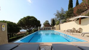 A swimming pool with lounge chairs and a pergola.