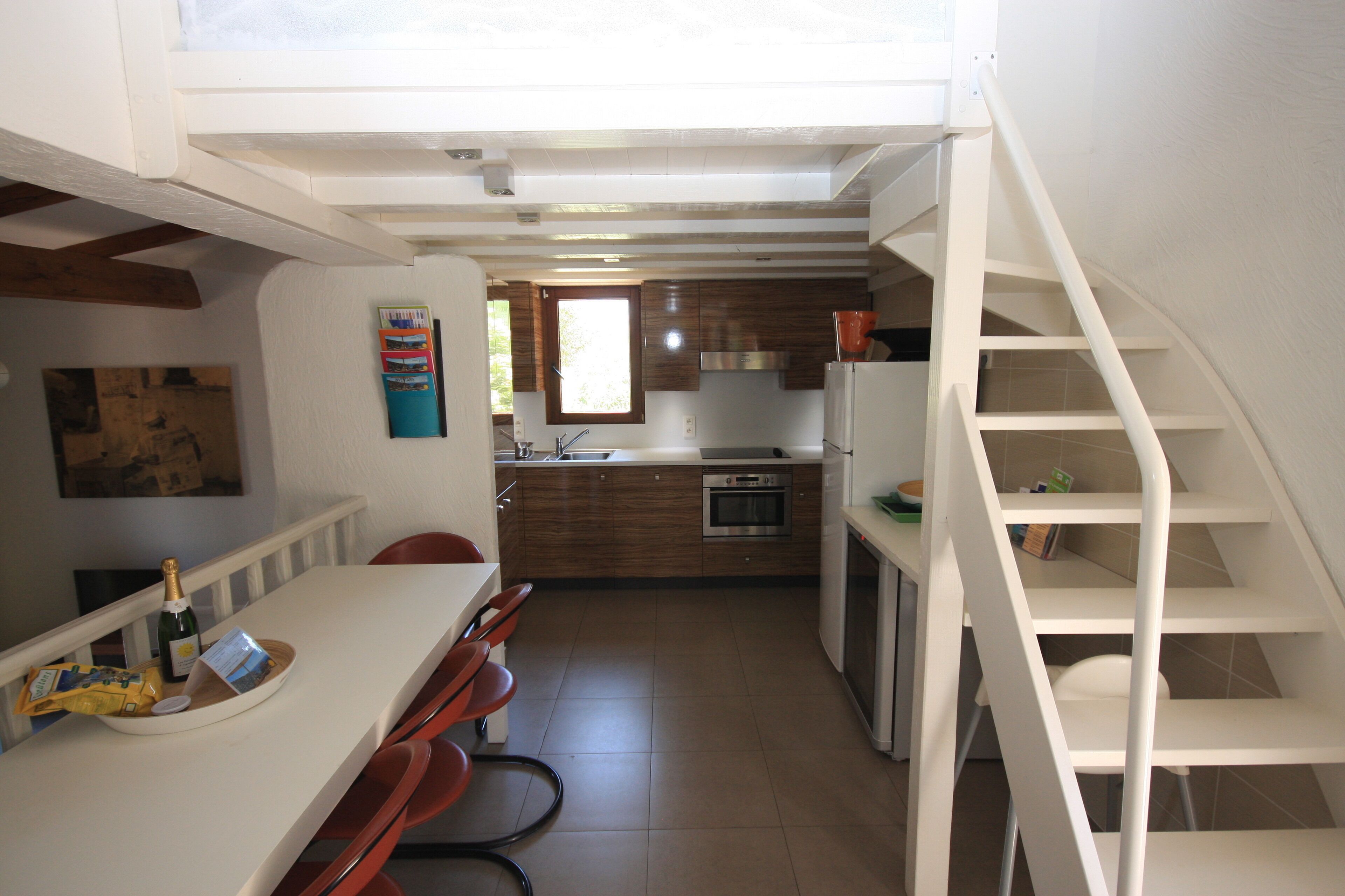 Une cuisine compacte comprenant un coin repas, un escalier et une fenêtre qui laisse entrer la lumière naturelle.
