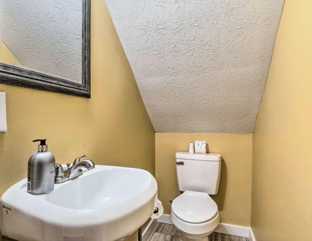 A bathroom with a white sink, a toilet, and a mirror.