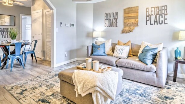 A living room with a grey sofa, blue and gold cushions, a coffee table, and a rug. There is a wall with the text "Fountain Square" and "Fletcher Place". - Urban Chic Townhome Near Downtown (Indianapolis)