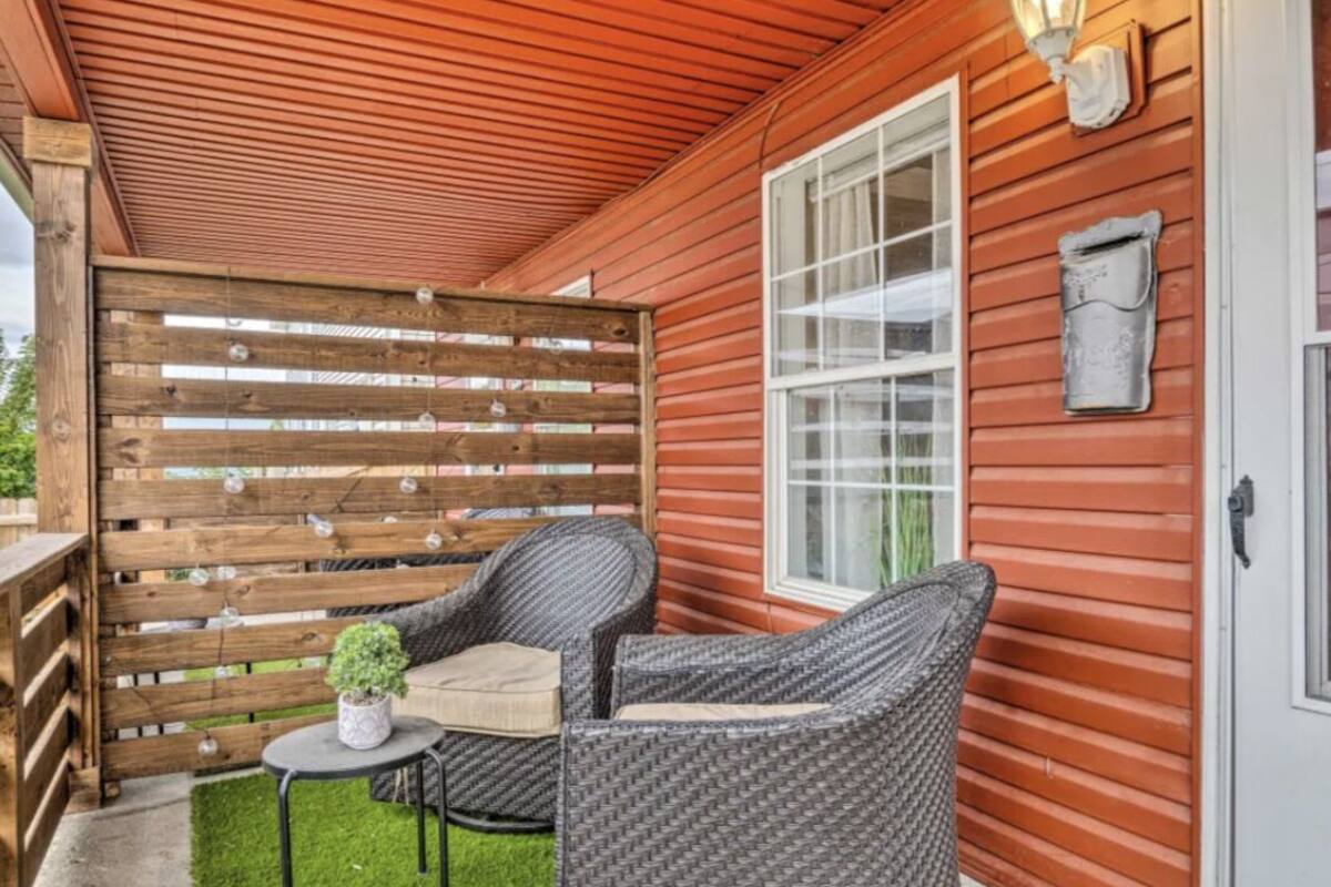 Eine Holzhütte mit überdachter Veranda, zwei Korbstühlen, einem kleinen Tisch und einem Blumentopf.