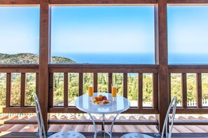 A balcony with a table set for breakfast, overlooking a coastal landscape. - Vissala 4 Minuartia in Chortata (Lefkada)