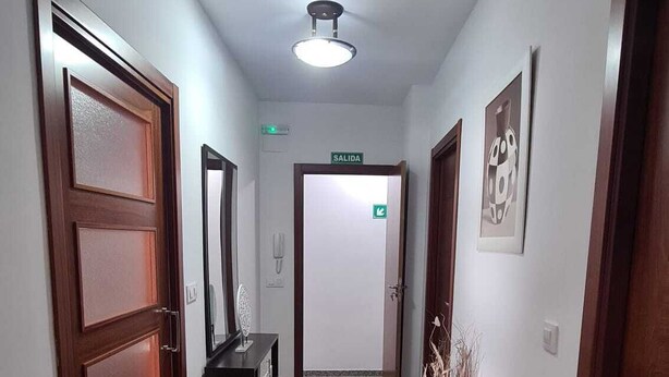 Un pasillo con puertas de madera, un mostrador de recepción y un letrero que indica la salida.