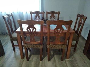 Une table à manger entourée de six chaises en bois, chacune dotée d’un siège recouvert d’un tissu tissé.