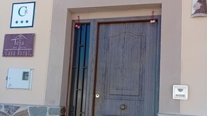 Una puerta de madera rústica con una reja metálica, un muro de piedra y unos pocos escalones que conducen a la puerta.