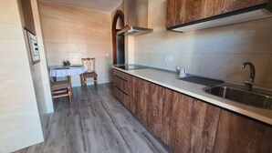 Una cocina moderna con encimera de madera, un lavamanos integrado y un comedor con mesa y sillas.
