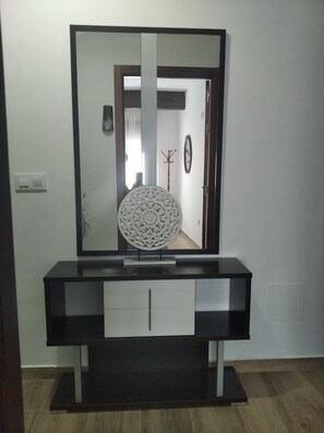 Un meuble-lavabo moderne doté d’un grand miroir, d’un élément décoratif mural et d’un porte-manteau.