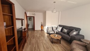 Una sala de estar moderna con un sofá gris, una mesa de centro de madera y un televisor sobre un mueble de madera.