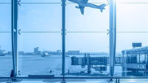 An airport terminal with a large glass window, a jet bridge, and a tarmac with an airplane. - Skycity b&b (Naples)