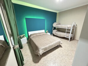 A bedroom with a large bed, a bunk bed, green curtains, and a white nightstand. - Skycity b&b (Naples)