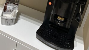 A kitchen area with a coffee maker, a basket of bread, and a bag of snacks on a shelf. - Skycity b&b (Naples)