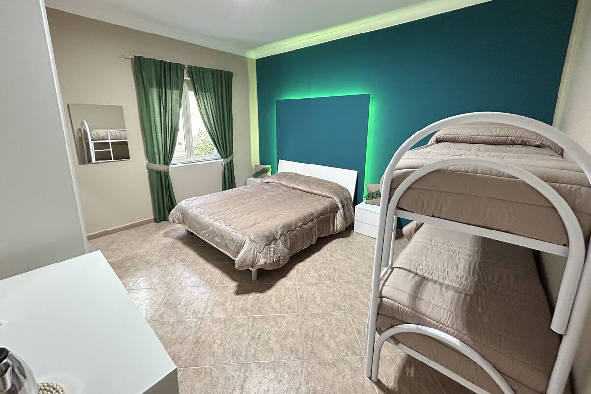 A room with two beds, a desk, and a window with curtains.