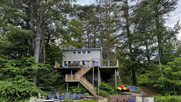A cabin with a deck and a dock, surrounded by dense forest. - Valhalla!! (Ludlow)