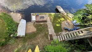 A backyard with a wooden deck, a small wooden structure, and a garden area with plants. - Valhalla!! (Ludlow)