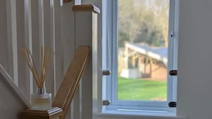 Un escalier avec une rampe en bois et une fenêtre donnant sur un paysage verdoyant.