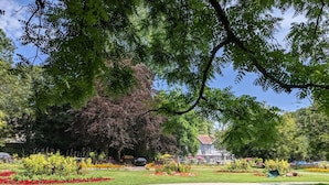 Un jardin bien entretenu, agrémenté de nombreuses fleurs aux couleurs vives, et un sentier qui mène à une maison avec un toit rouge.