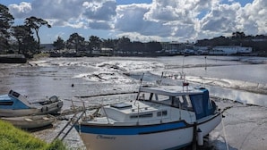 Un bateau était amarré sur une plage de sable, sous un ciel dégagé parsemé de nuages.