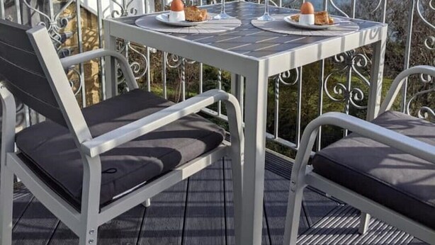 A balcony with a table set for breakfast, overlooking a scenic view. - 2 Bed Apartment The Priory - Panoramic Sea View (Shanklin)