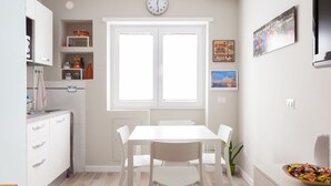 A modern kitchen with white cabinetry, a white dining table, and chairs. There is a window with a clock above it, and a pizza-themed sign on the wall. - A Passino from St. Peter's (Roma)