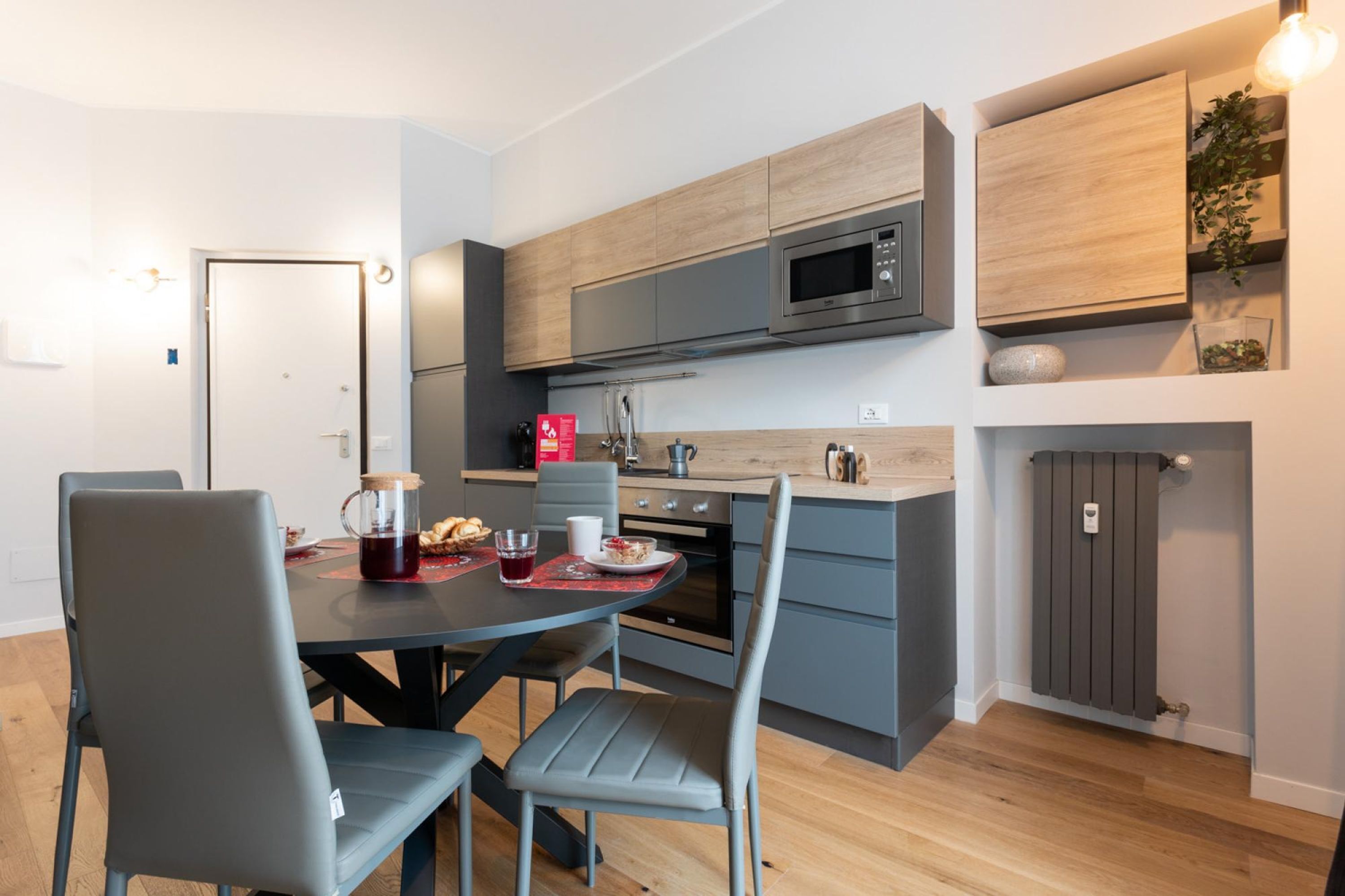 Una cocina moderna con armarios grises, un microondas integrado y una zona de comedor con mesa y sillas.