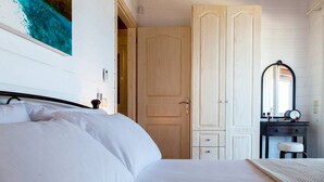 A bedroom with a bed, a wardrobe, a vanity with a mirror, and a painting on the wall. - Vissala 5 Alkanna in Chortata (Lefkada)