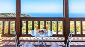 A table with breakfast items and drinks on a balcony with a view of the sea. - Vissala 5 Alkanna in Chortata (Lefkada)