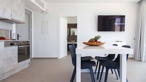 A modern kitchen with a built-in oven and a dining area with a white table and black chairs. - Syvota 5 Sunset 1B Valentina (Igoumenitsa)