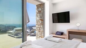A hotel room with a bed, a TV, and a view of the sea. - Syvota 5 Sunset 1B Valentina (Igoumenitsa)