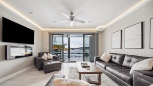 Uma sala de estar moderna com sofás de couro, uma televisão de tela plana e um ventilador de teto.