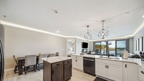 Uma cozinha moderna com armários brancos, uma ilha central e iluminação pendente.