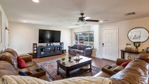 Ein Wohnzimmer mit Ledersofas, einem Couchtisch, einem Fernseher und einem Deckenventilator.