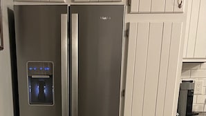 Ein Edelstahl-Kühlschrank mit Wasserspender, eingebautem Backofen und separatem Gefrierfach.