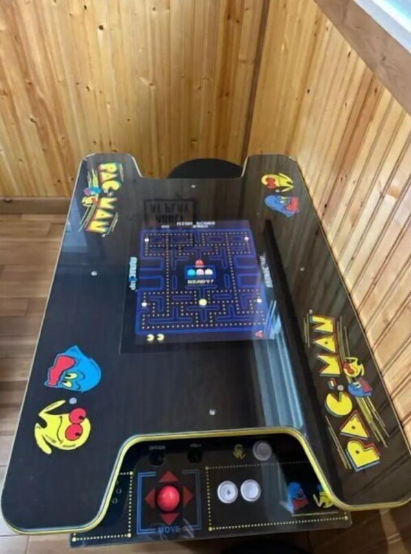 A Pac-Man arcade game table with a joystick and buttons, surrounded by wooden paneling.