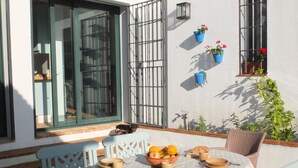 Een terras met een eettafel, omringd door rieten stoelen.