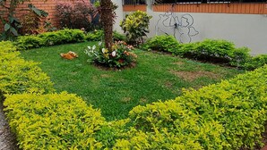 A landscaped garden with neatly trimmed hedges, a palm tree, and a small statue. - Cuarto Privado a 10 Minutos del Parque Kennedy (Lima)