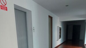 A long, empty hallway with a brown floor, white walls, and a door at the end. - Cuarto Privado a 10 Minutos del Parque Kennedy (Lima)