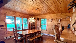 L’intérieur d’un chalet en bois rustique, avec une grande table à manger, des bancs et un lustre.